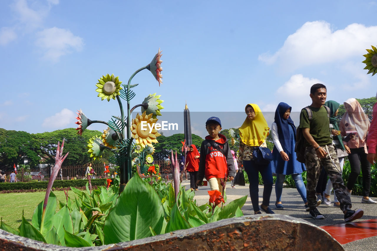 GROUP OF PEOPLE ON PLANTS AGAINST SKY