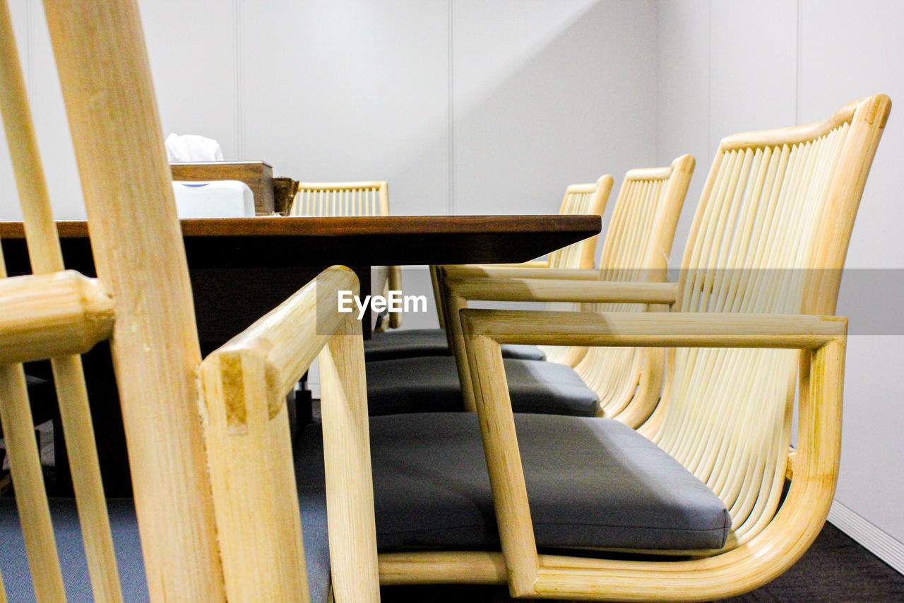 Empty chairs and table against wall at office