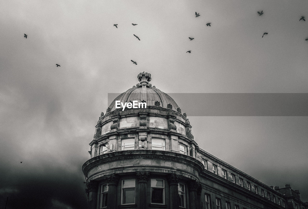 architecture, black and white, building exterior, built structure, monochrome, sky, bird, flying, dome, monochrome photography, animal themes, animal, low angle view, wildlife, nature, animal wildlife, travel destinations, large group of animals, cloud, group of animals, no people, darkness, city, government, flock of birds, outdoors, building, white, travel
