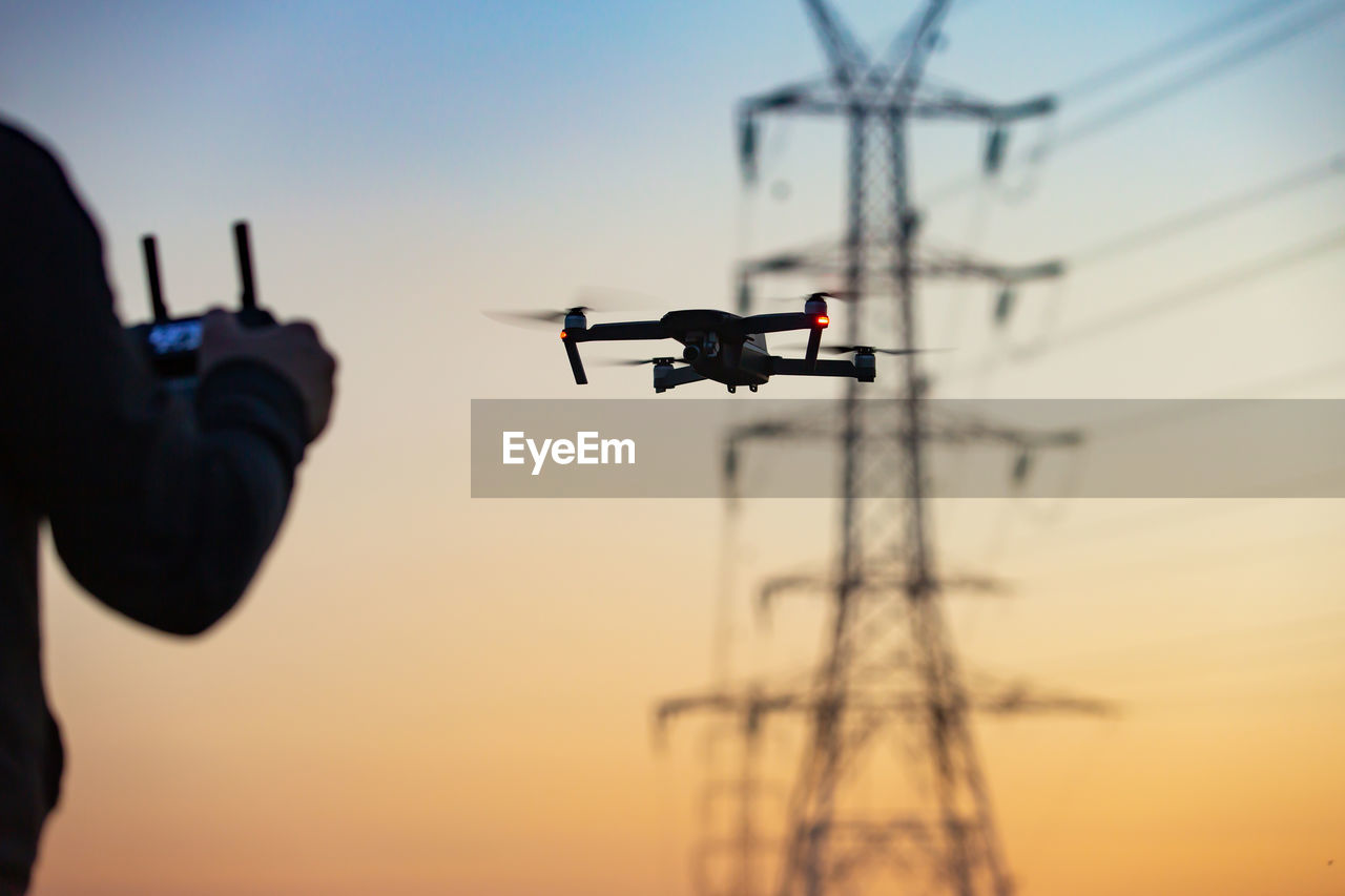 Drone pilot operating an uav in proximity to electric pylons and energy lines.