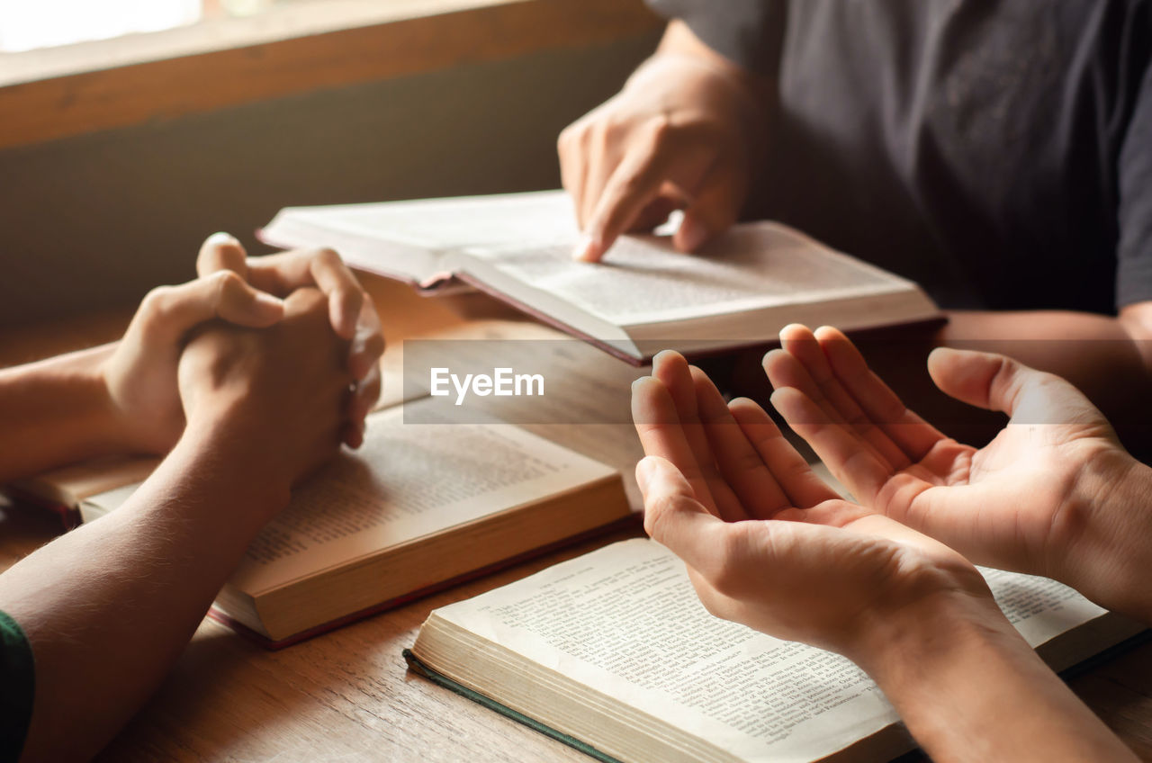 Midsection of person holding book on table