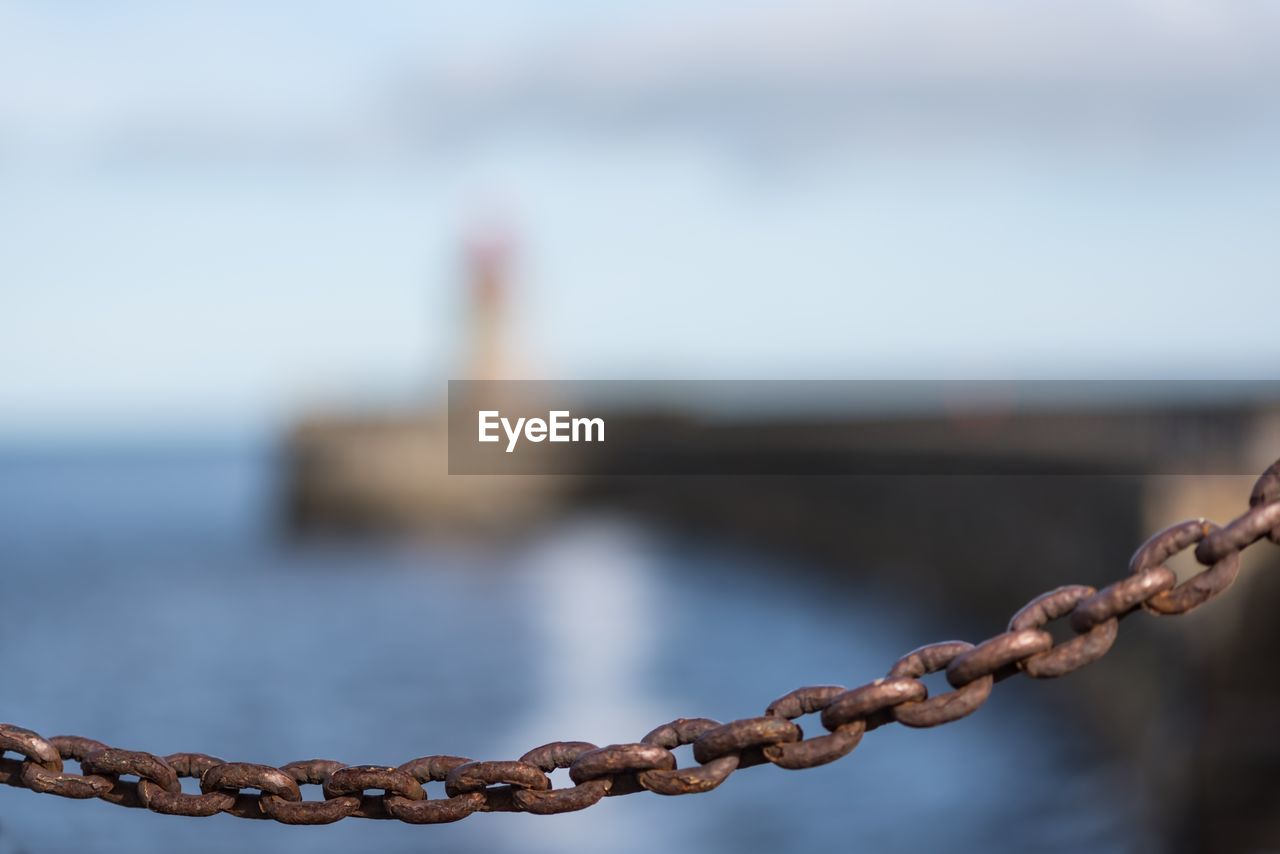 Close-up of chain against sea against sky