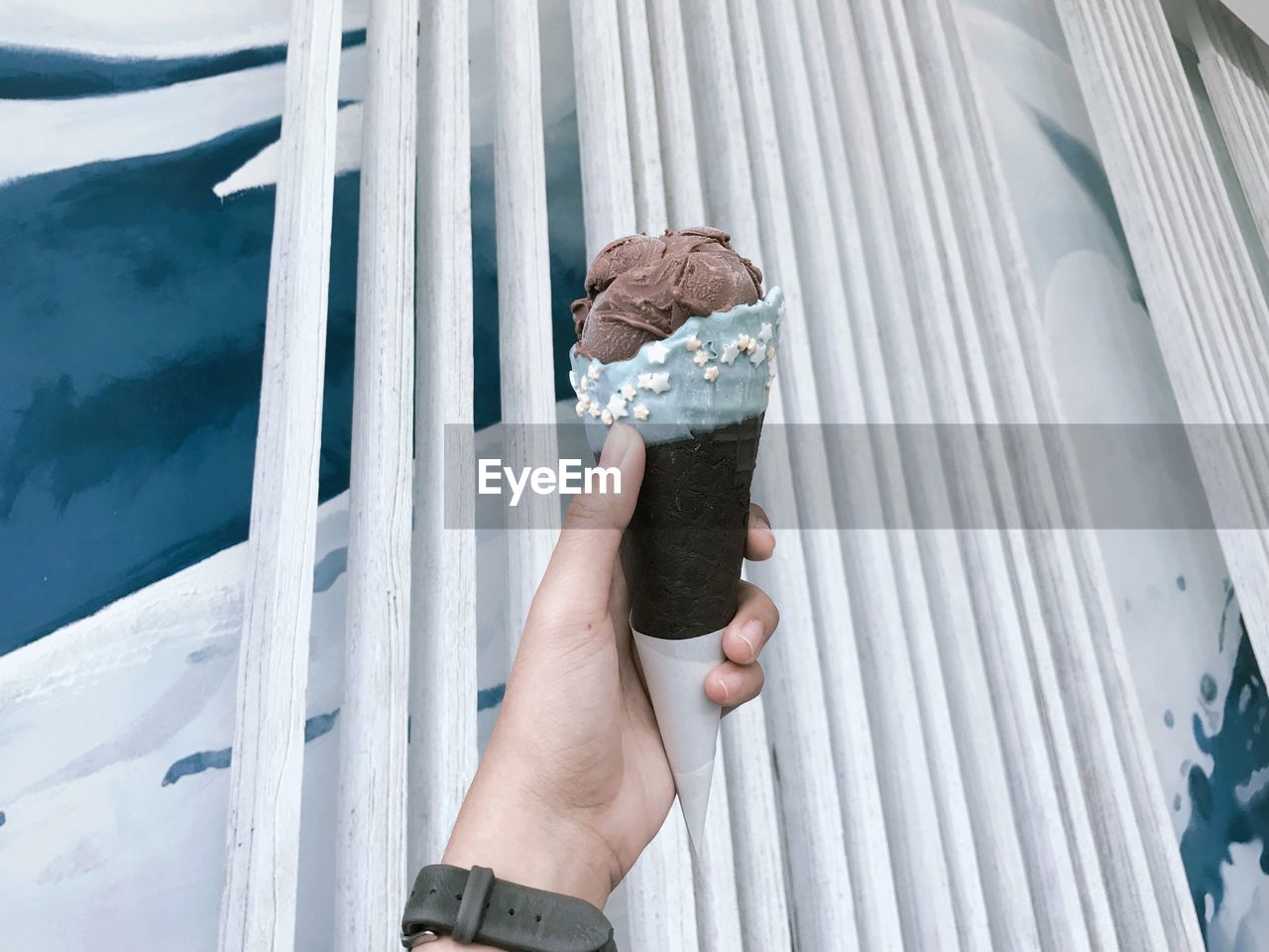 Cropped hand of person holding ice cream cone outdoors