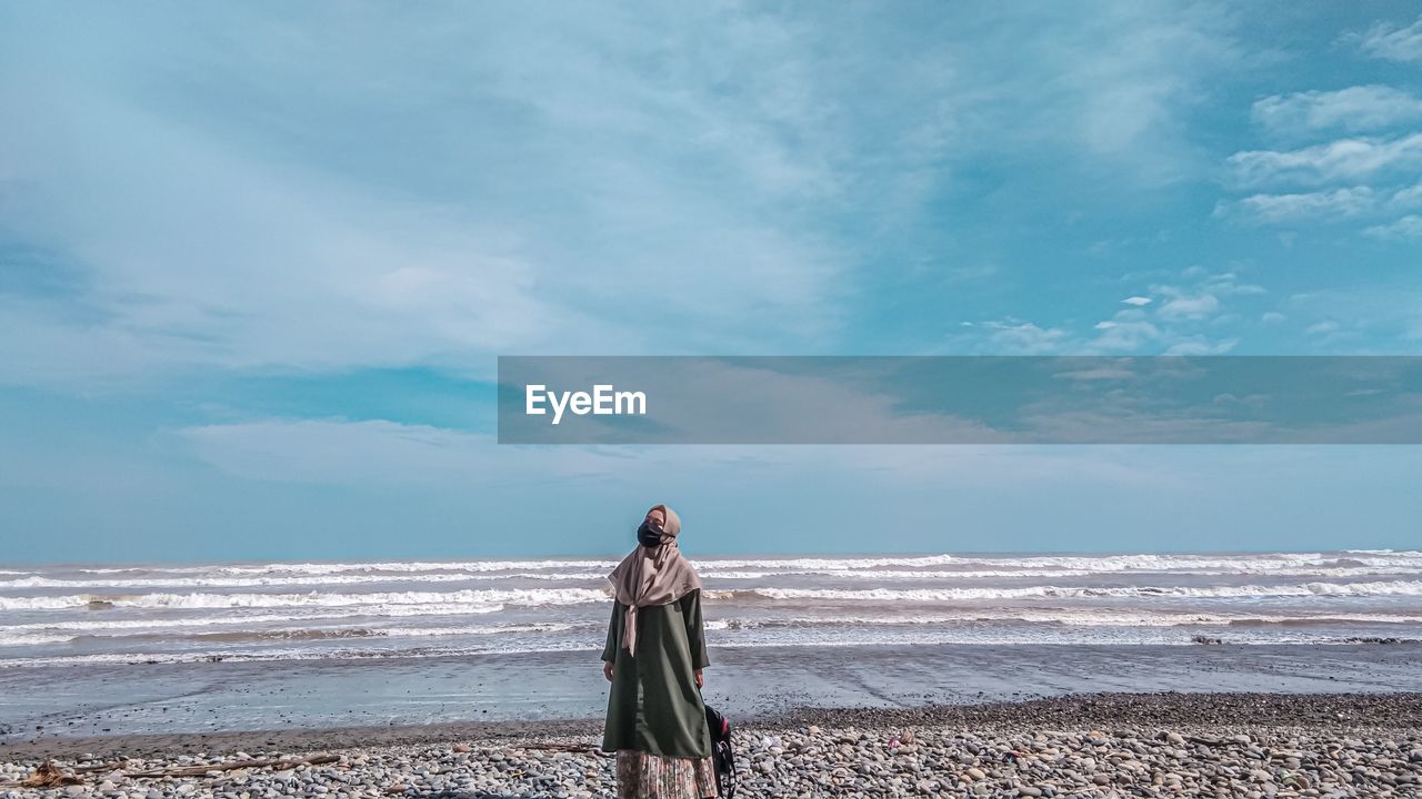 Woman standing on beach against sky