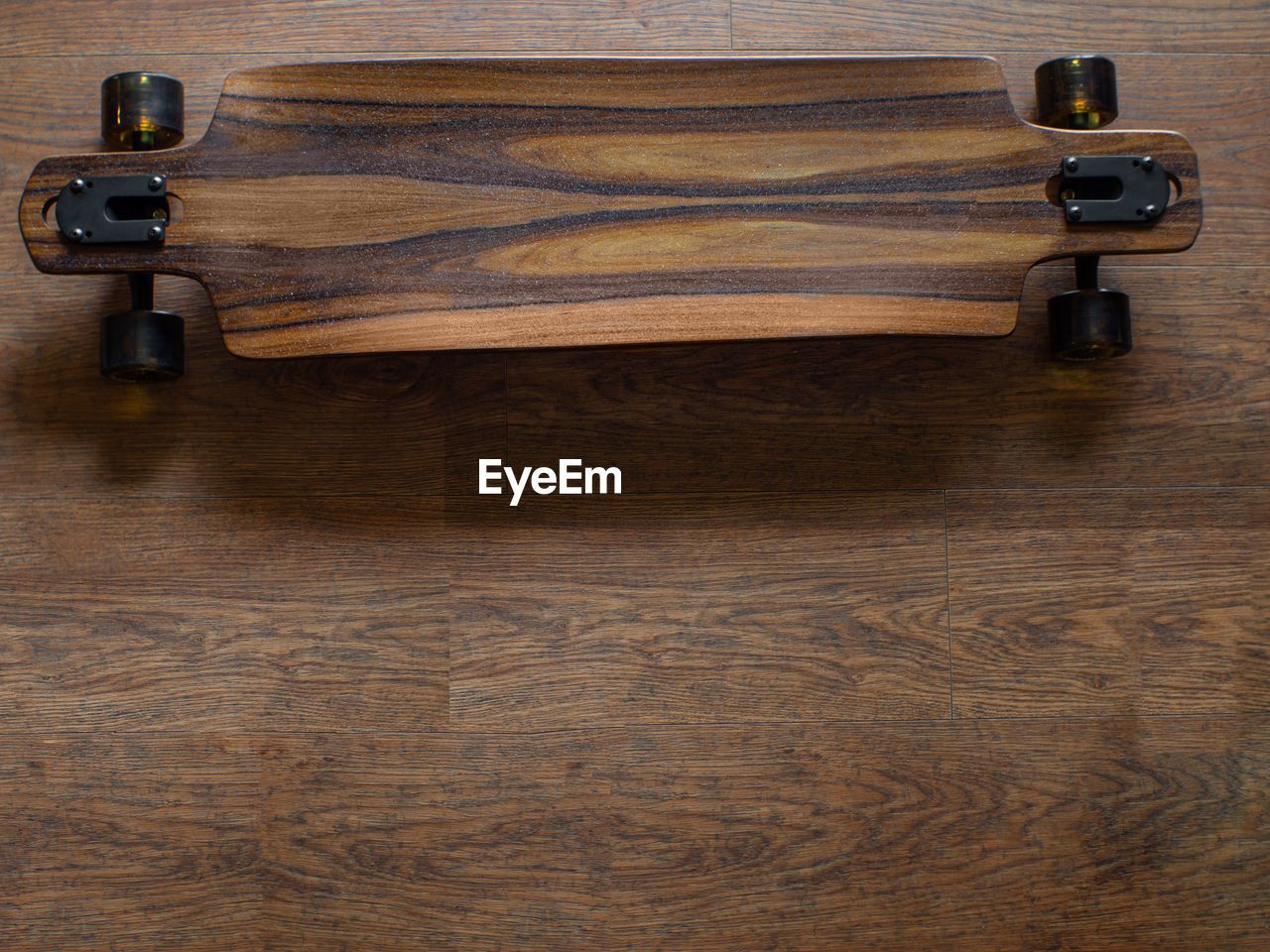 Top view to the part of brown longboard with brown rubber wheels and logo arbor. dark mood.