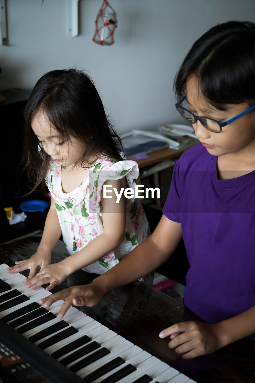 Happy kids playing piano at home