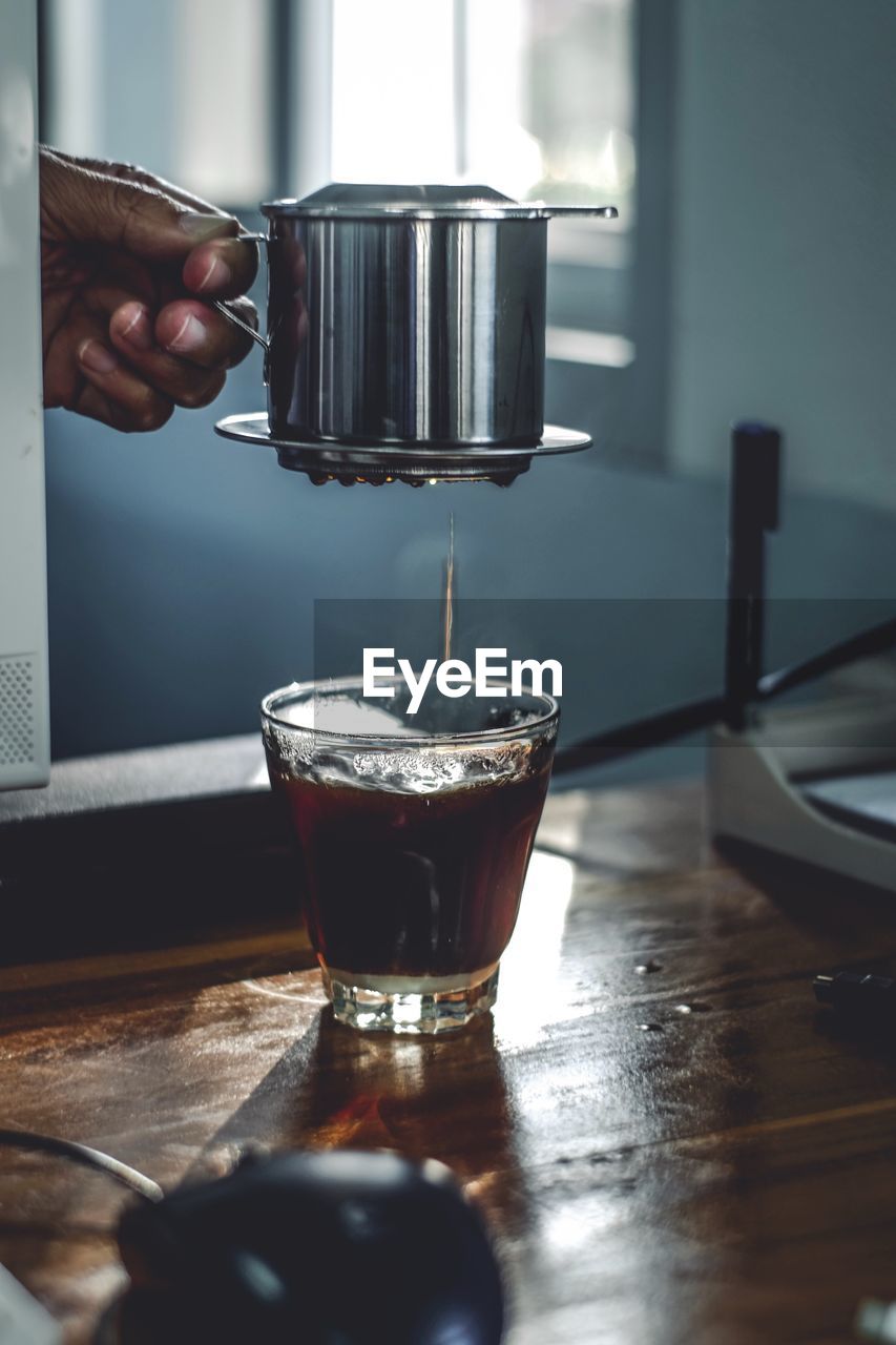 Cropped hand of man pouring coffee in glass