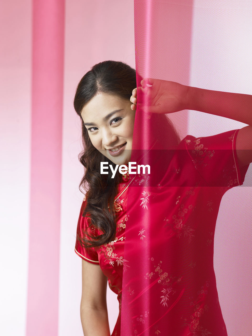 Portrait of woman standing by curtain