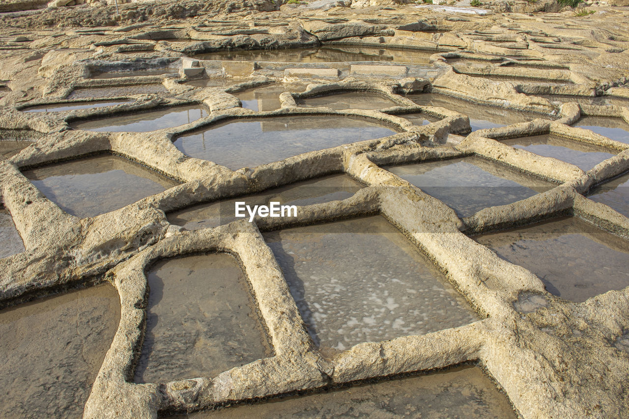 cobblestone, high angle view, day, pattern, road surface, no people, soil, nature, walkway, outdoors, sand, ancient history, wall, land, flooring, flagstone, full frame, sunlight, shape, archaeological site, stone wall