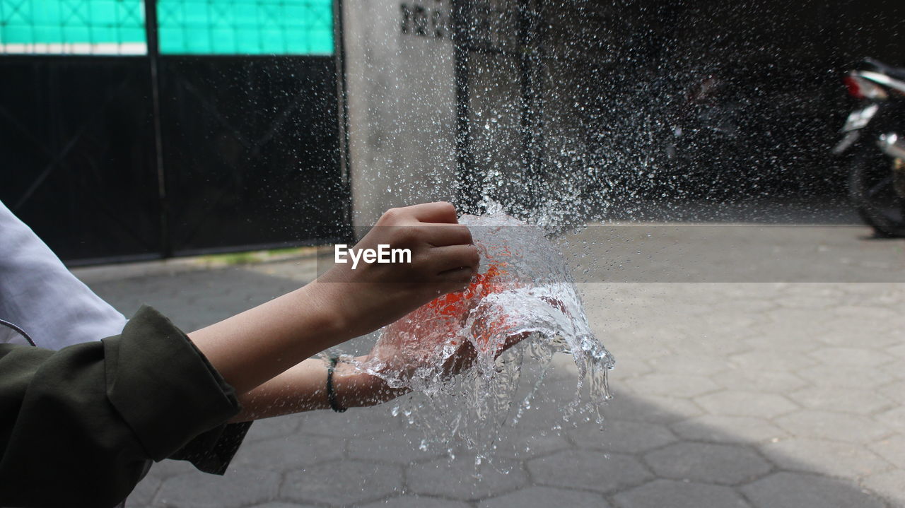 Midsection of men bursting water balloon