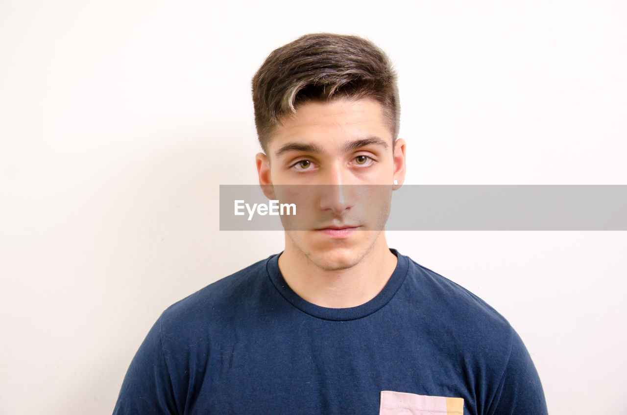 PORTRAIT OF HANDSOME YOUNG MAN AGAINST WHITE BACKGROUND