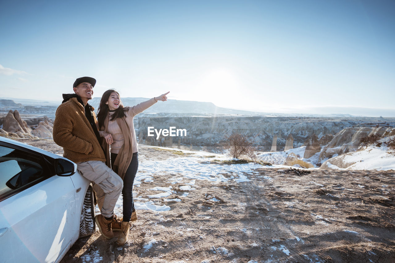 rear view of man with arms outstretched standing on snow covered landscape