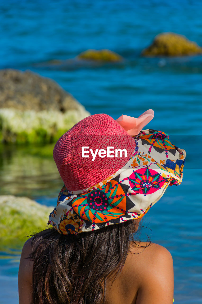 Rear view of woman in colorful hat at beach