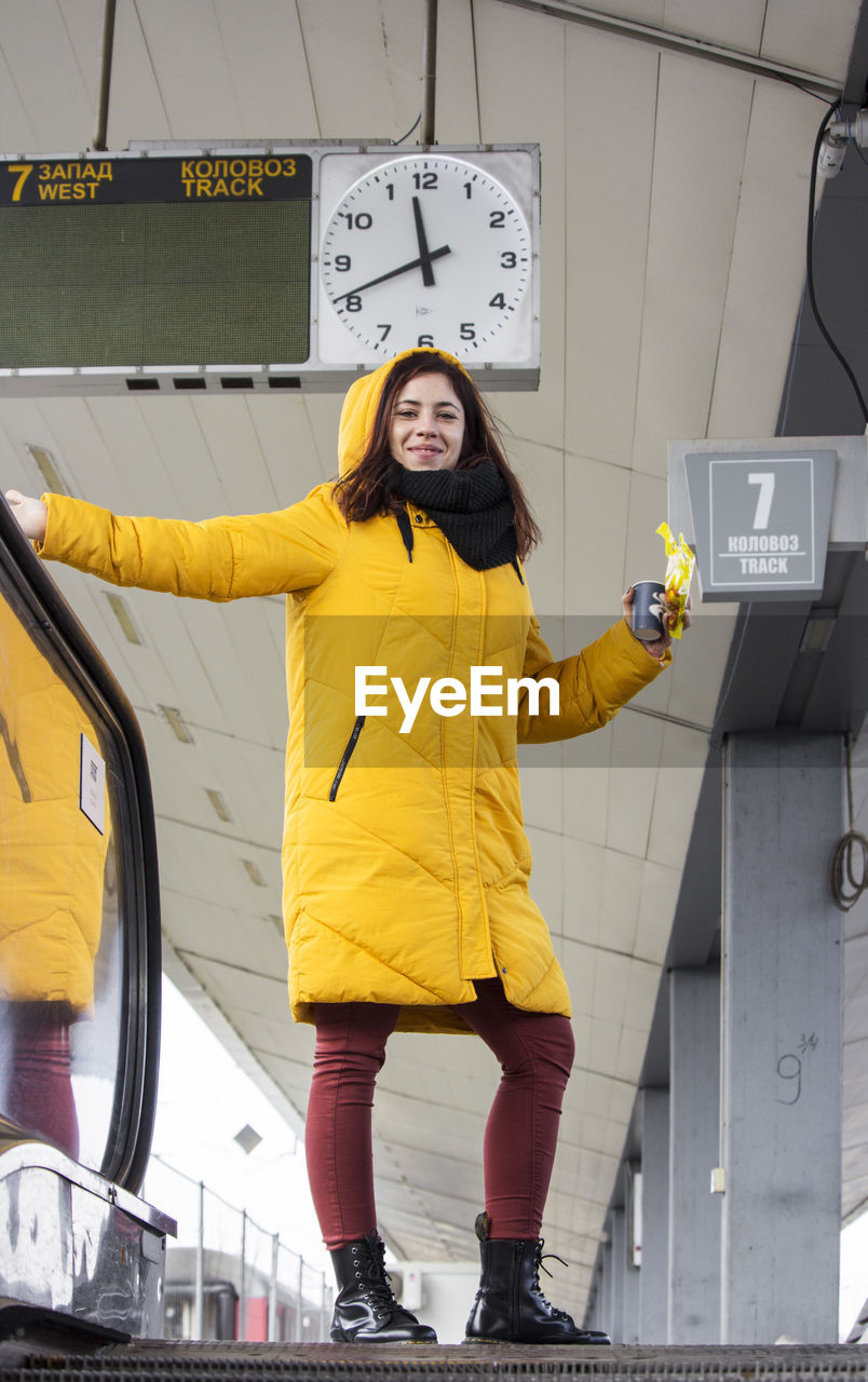 Young woman in yellow hood jacket at the train station