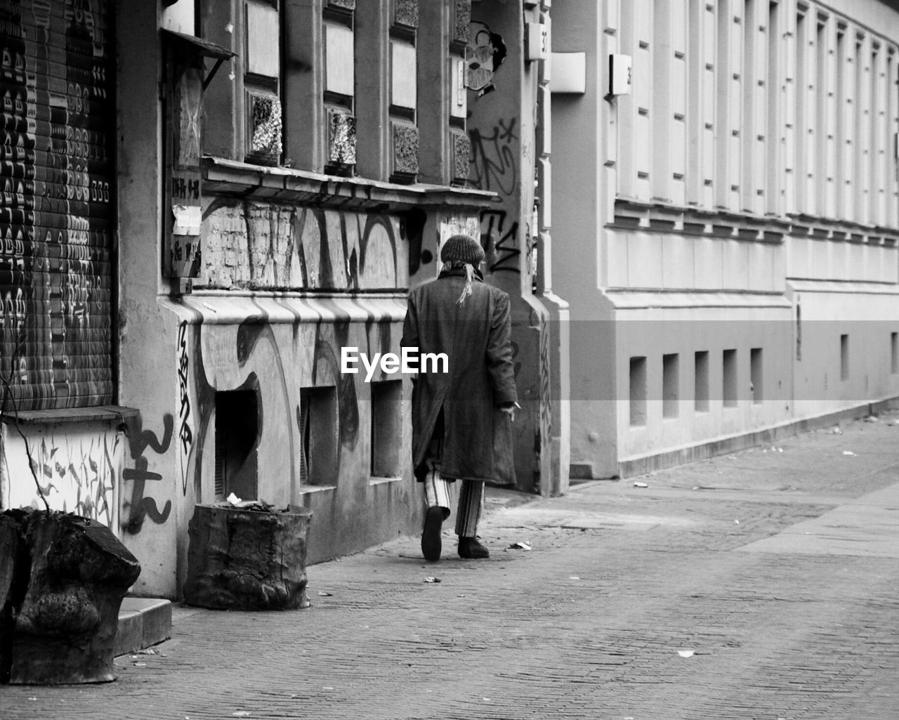 FULL LENGTH REAR VIEW OF MAN WALKING ON STREET