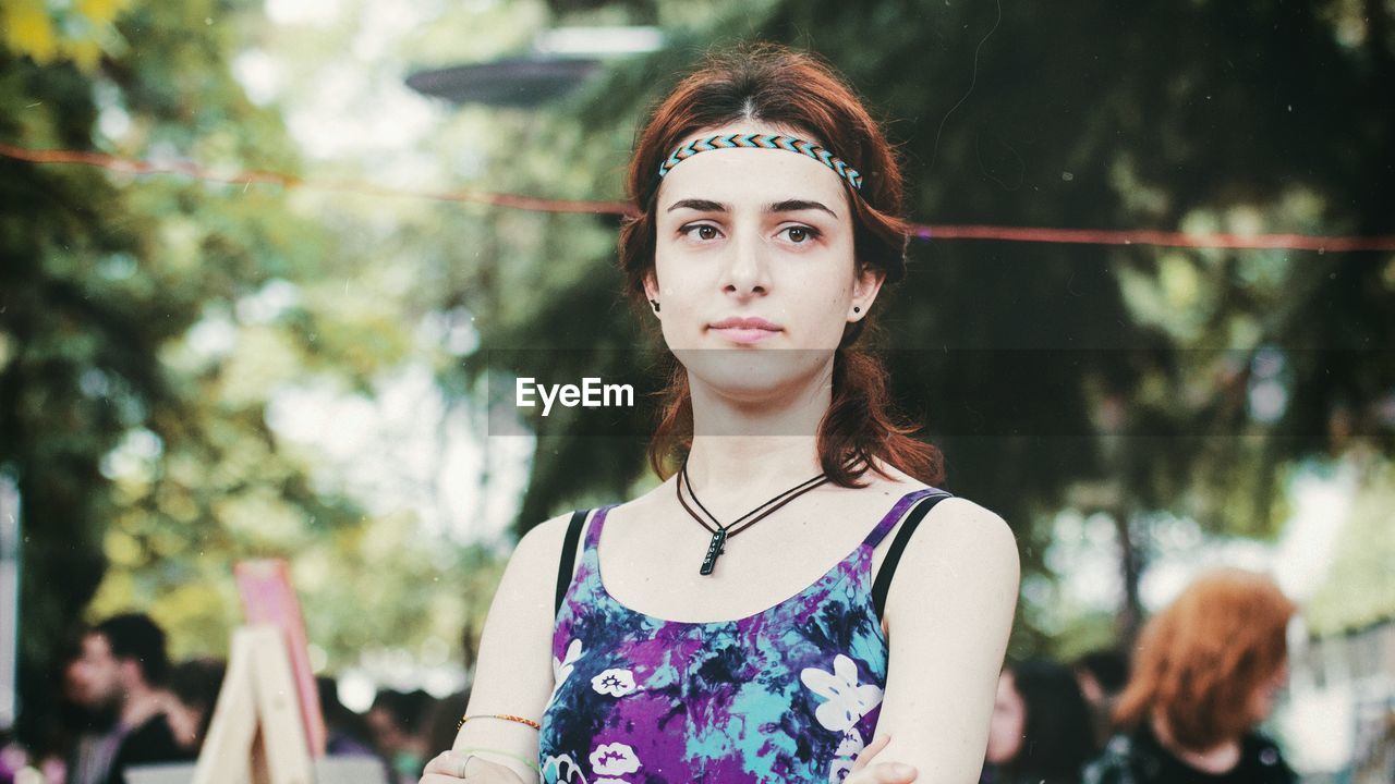 PORTRAIT OF BEAUTIFUL YOUNG WOMAN AGAINST TREES IN PARK