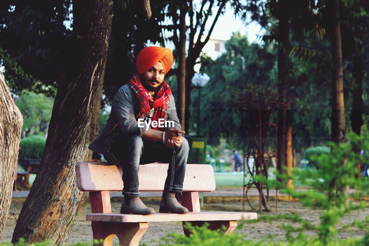 Portrait of smiling man sitting on seat against trees