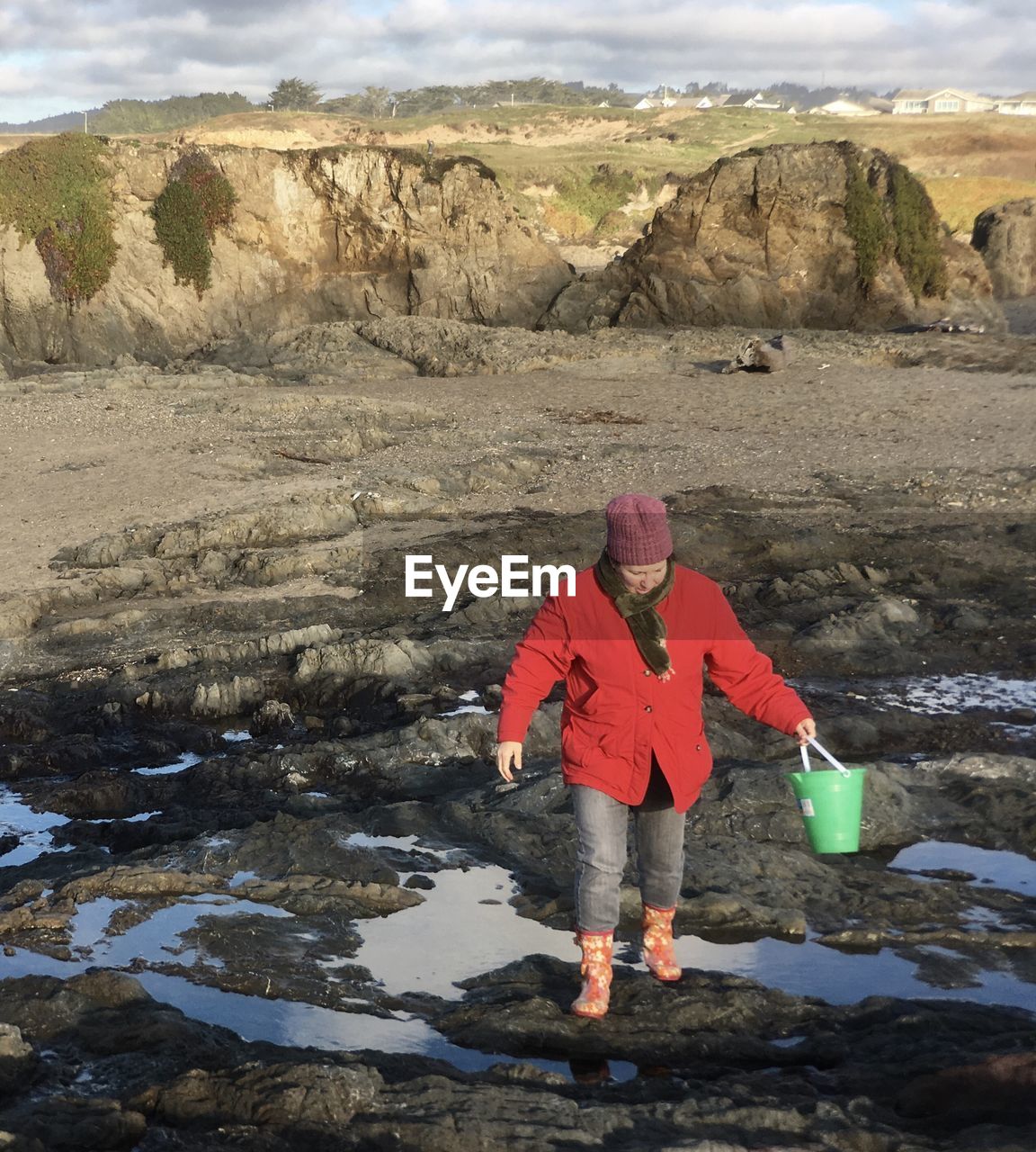 Full length of woman holding bucket while walking on rock