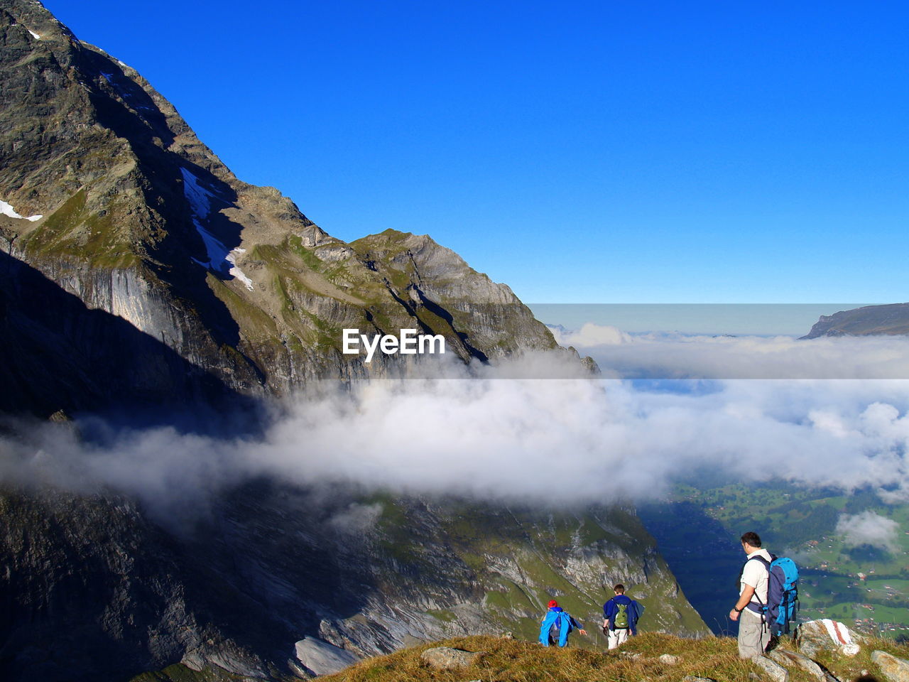 High angle view of friends walking on mountain against blue sky