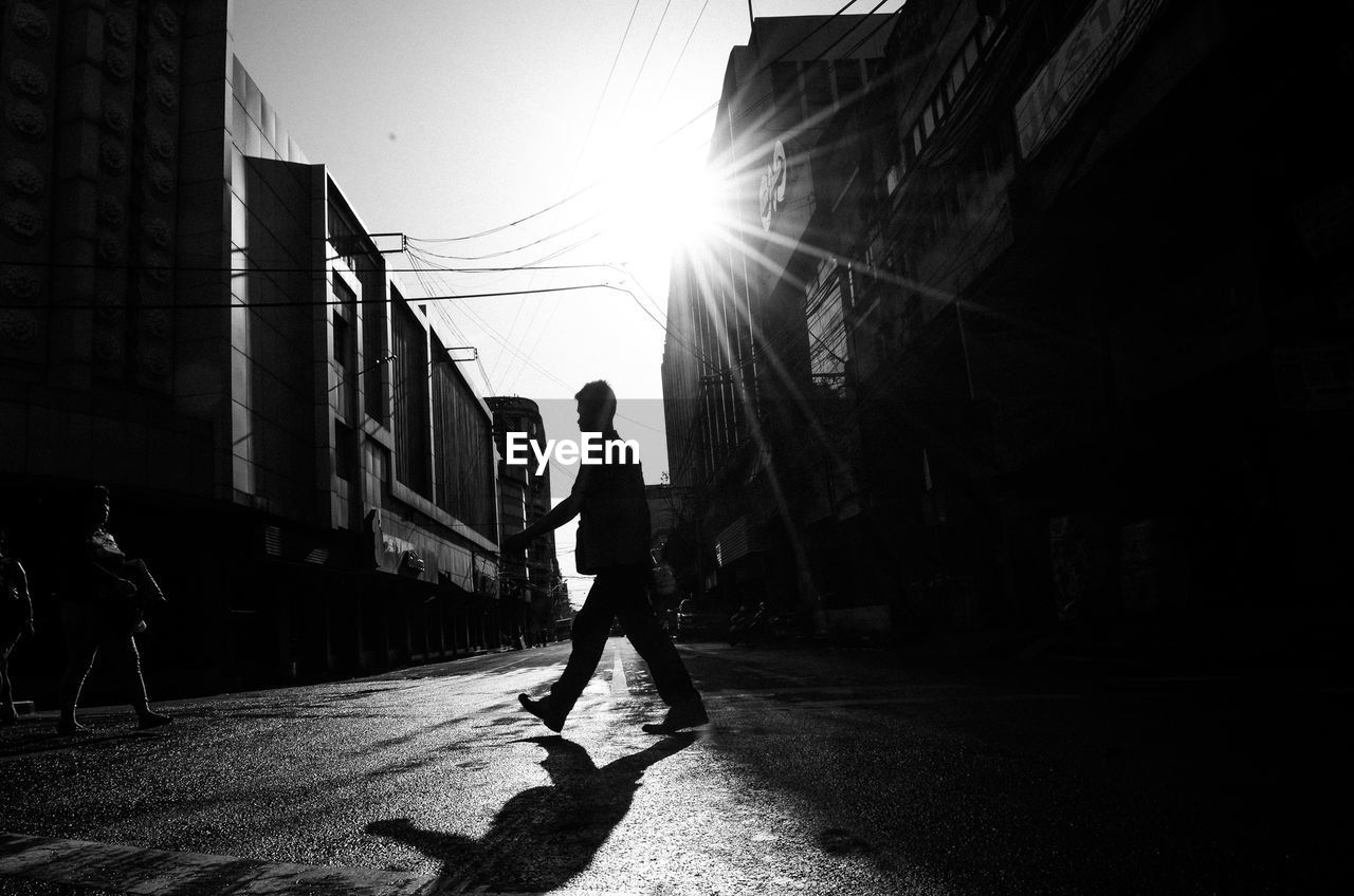 Side view of silhouette man walking on street in city