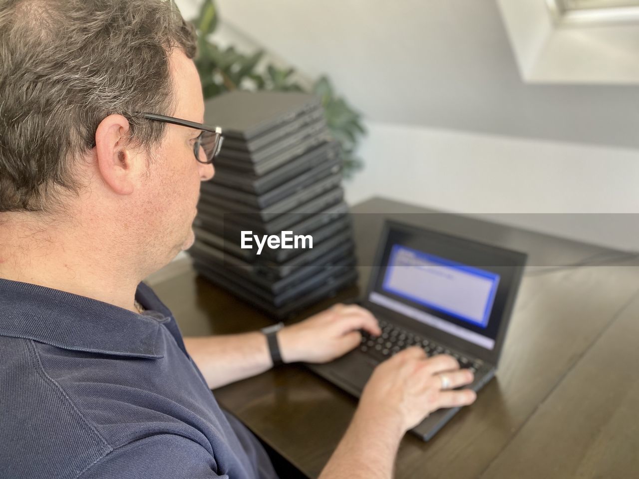 MIDSECTION OF MAN USING MOBILE PHONE IN LAPTOP