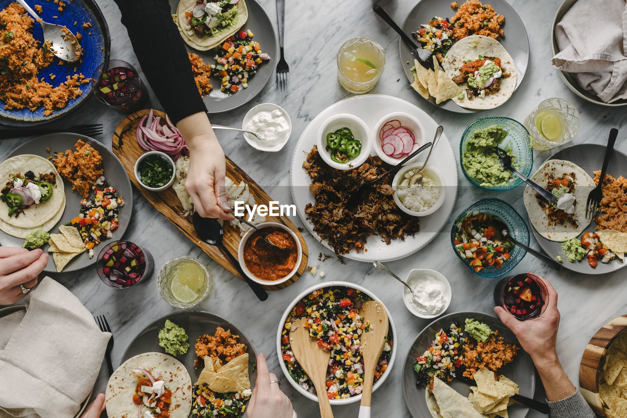 Cropped hands of friends having food at table during social gathering