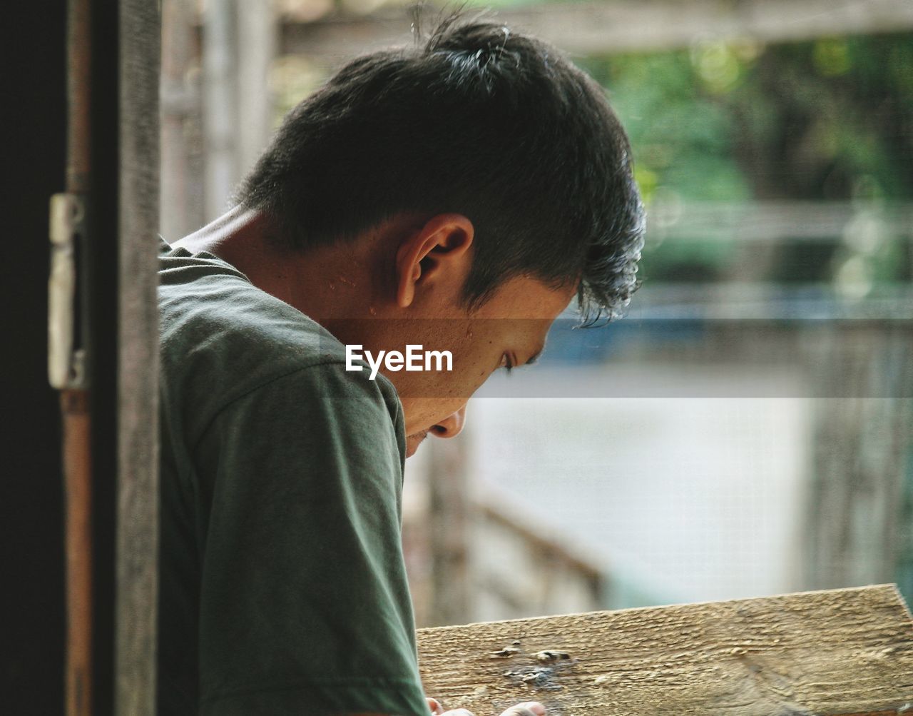 Side view of young man looking through window