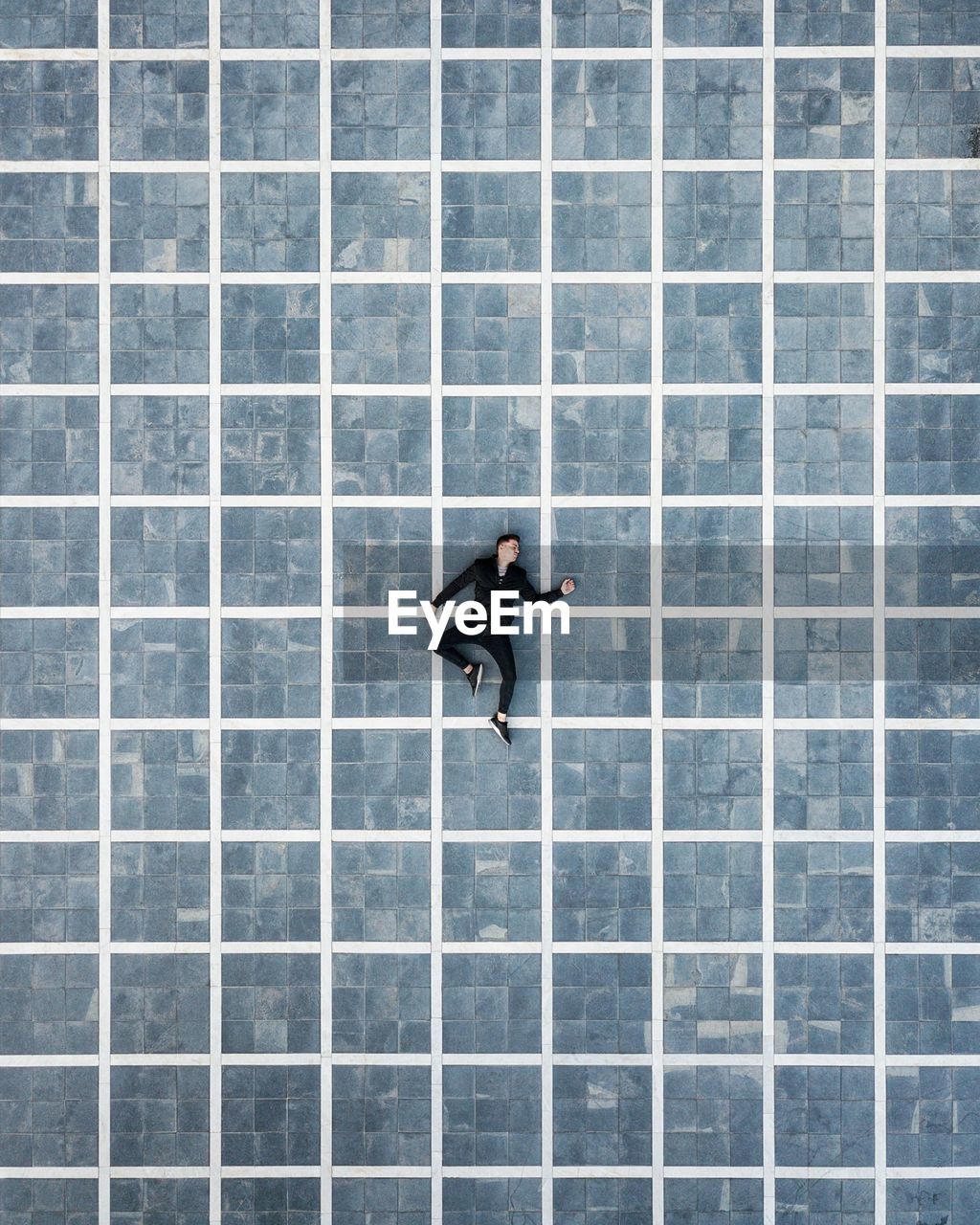 Directly above shot of man sleeping on tiled floor