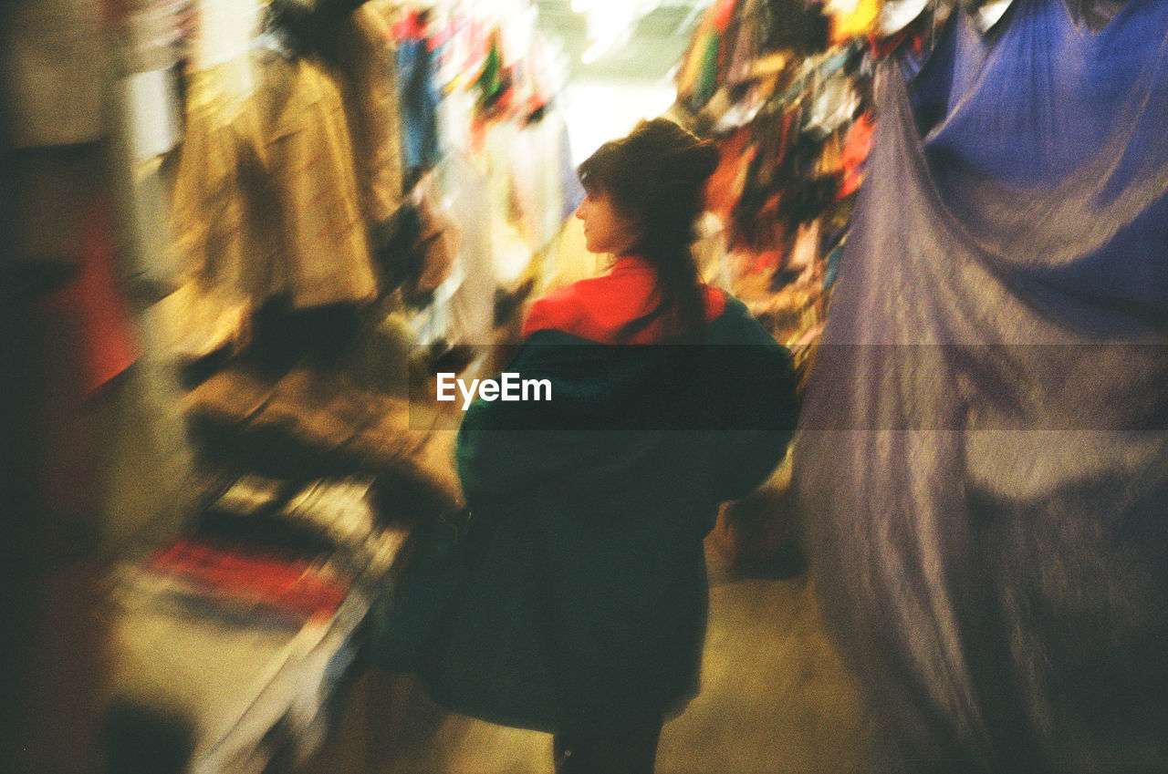 Defocused image of woman walking by stores in market