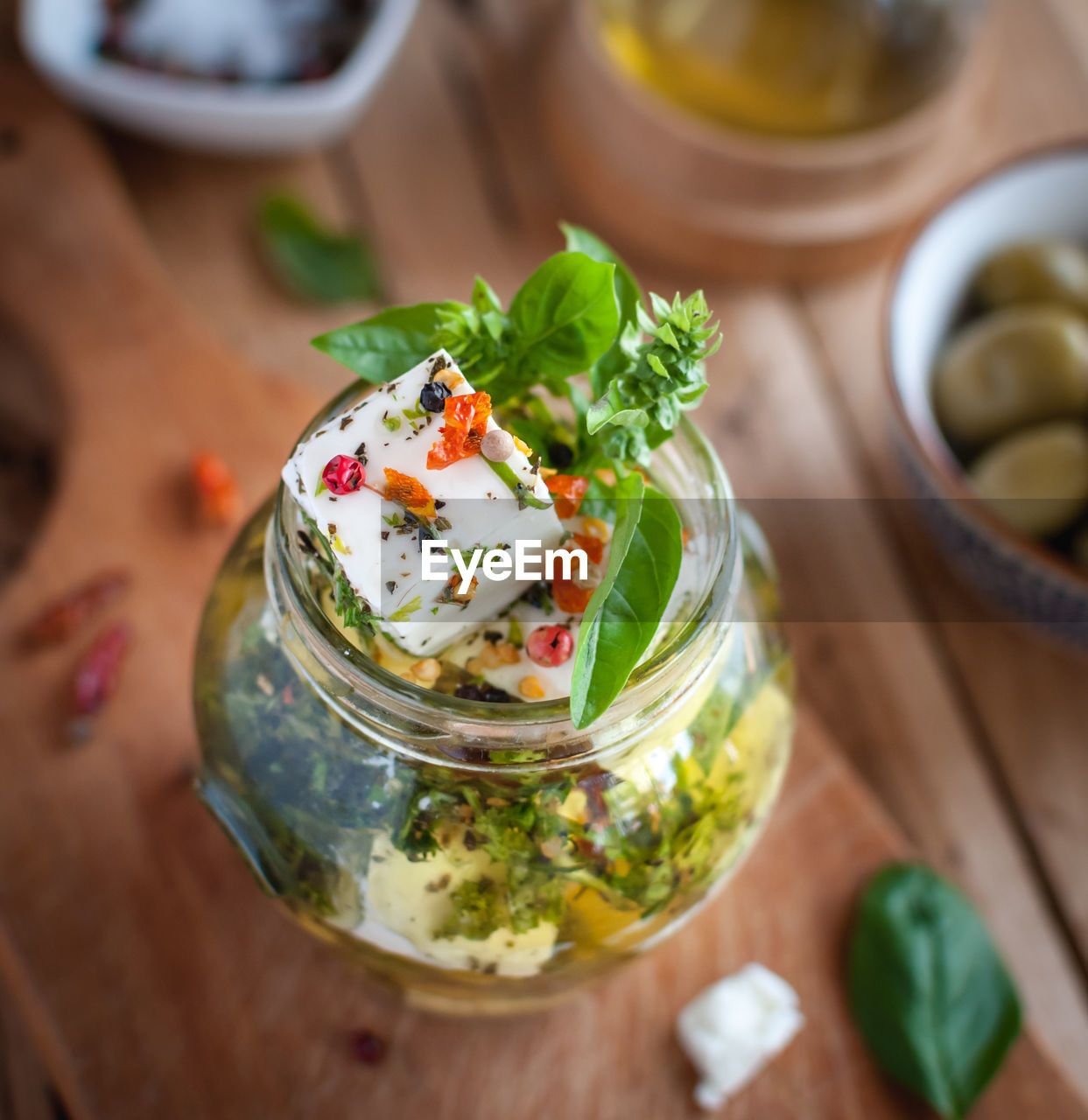 Close-up of marinated feta cheese in olive oil, herbs and red pepper flakes on wooden background