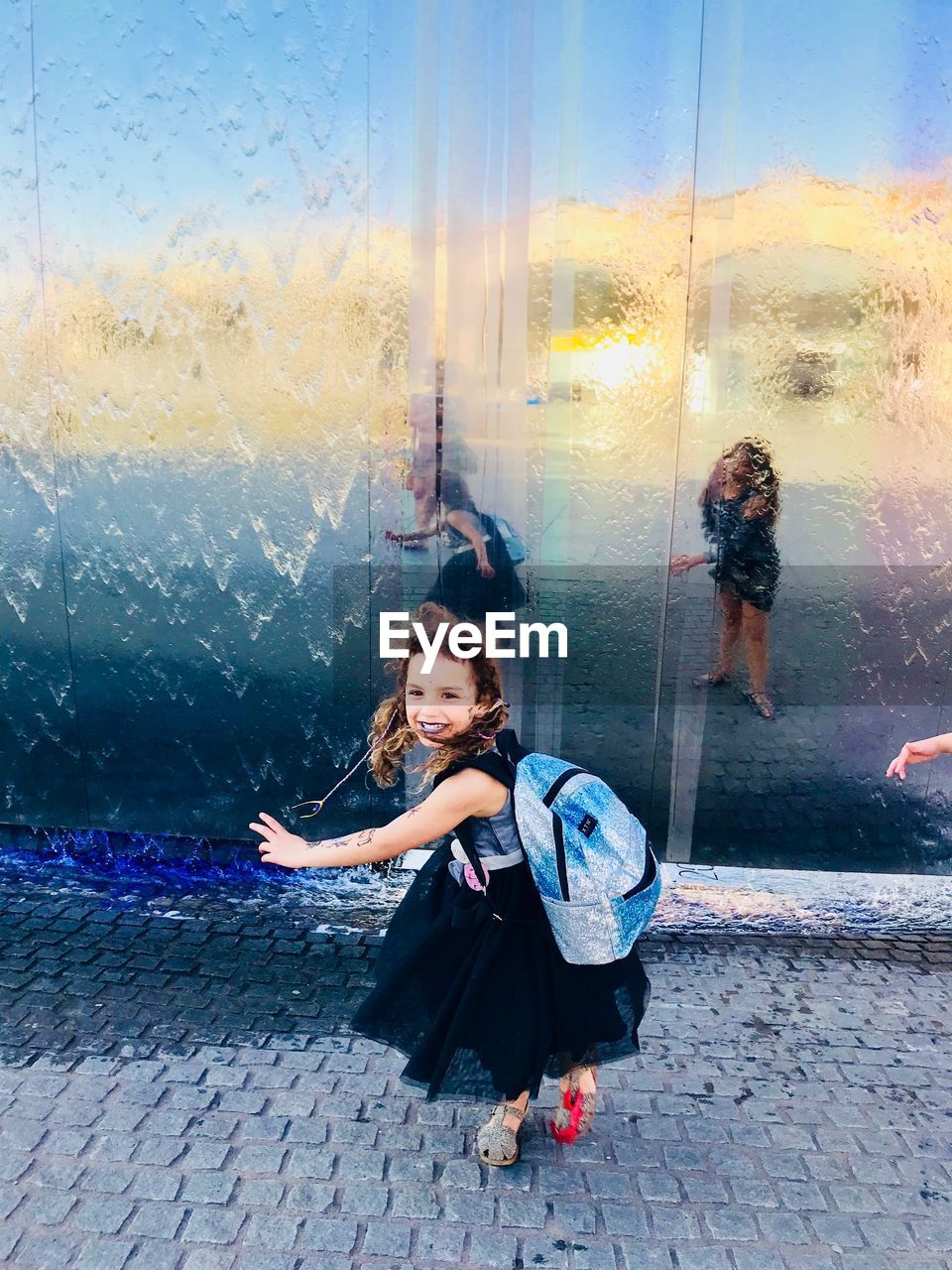 High angle view of smiling girl walking on footpath by glass