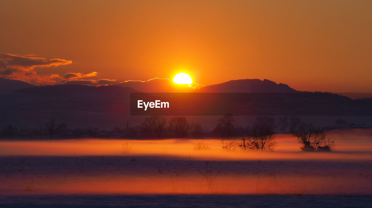 Scenic view of lake against orange sky