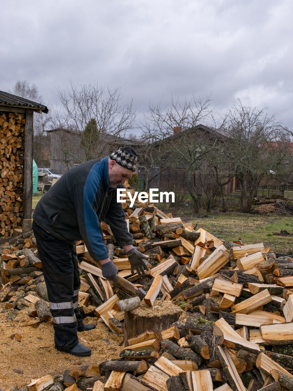 SIDE VIEW OF MAN SITTING ON LOG AGAINST SKY