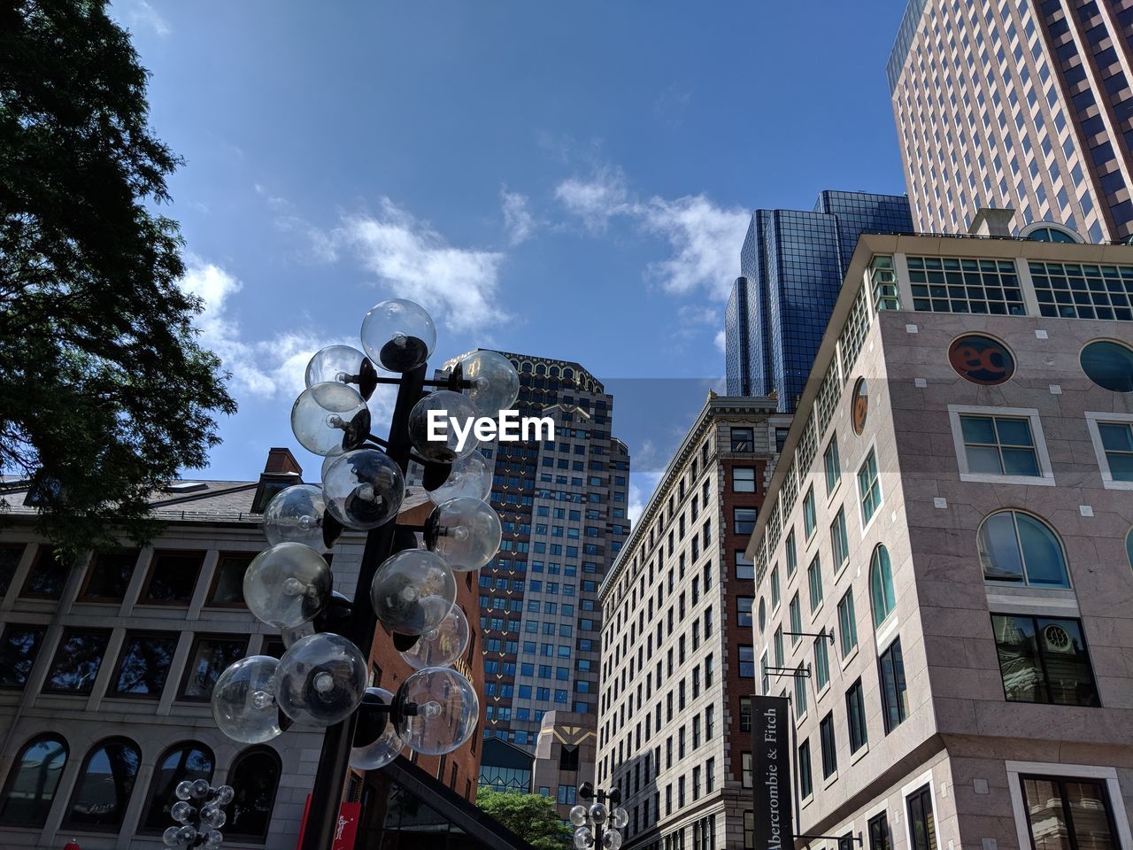 LOW ANGLE VIEW OF BUILDINGS IN CITY AGAINST CLOUDY SKY