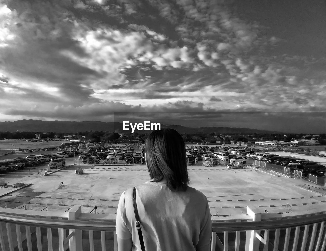Rear view of woman looking at cityscape against sky