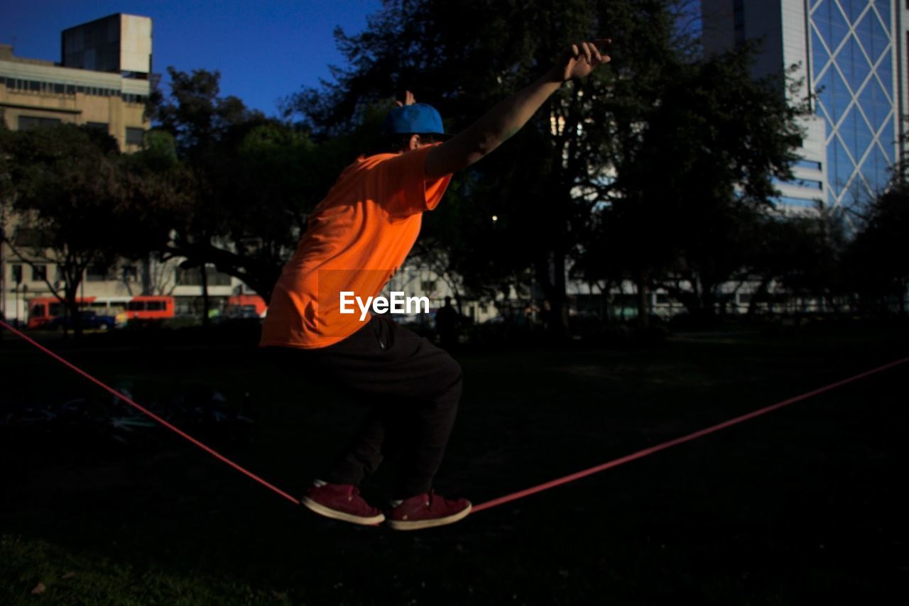 Boy with arms outstretched balancing on slackline at park