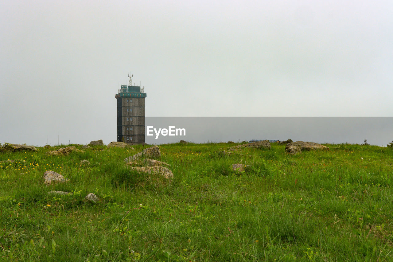 LIGHTHOUSE AMIDST FIELD AGAINST SKY