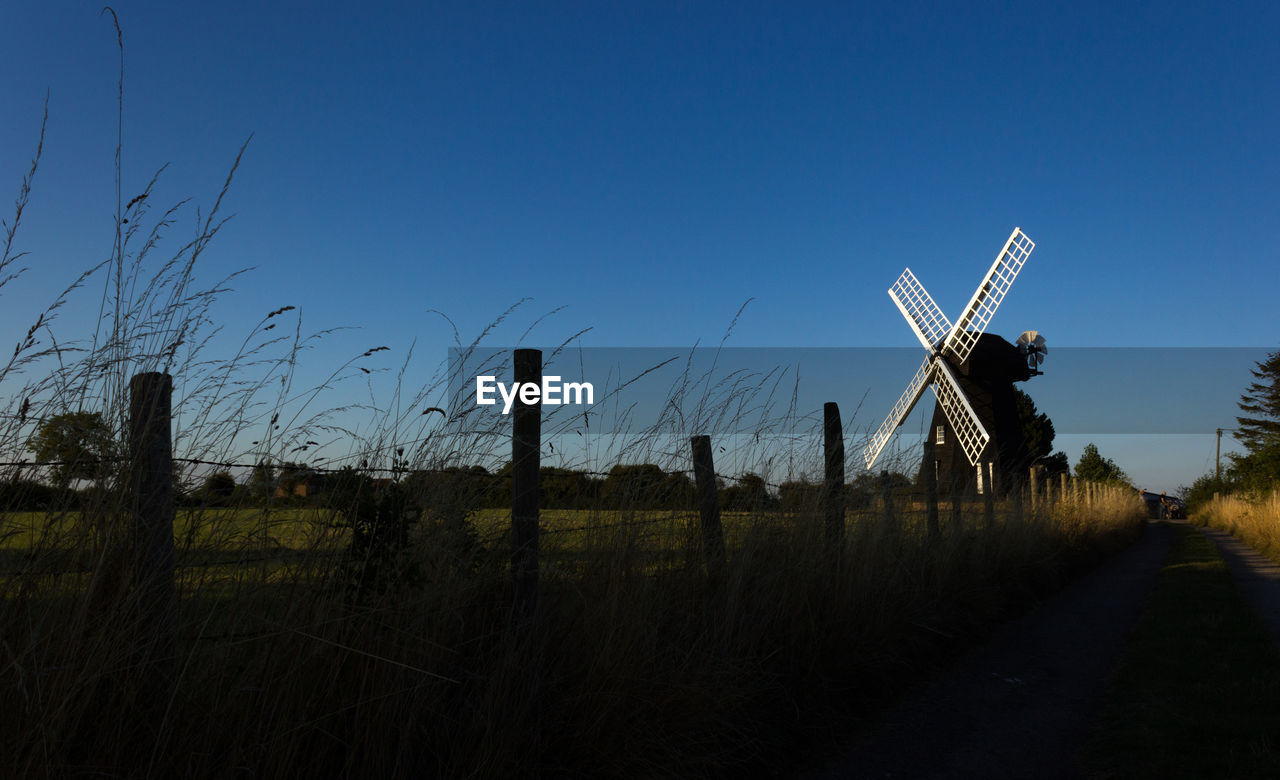 Traditional windmill on field against clear blue sky