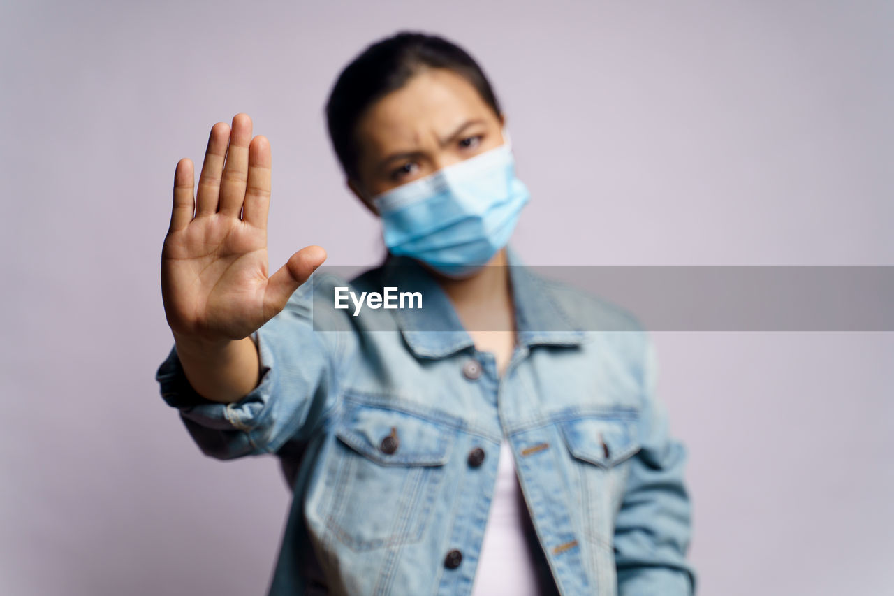 Portrait of young woman standing gesturing against gray background