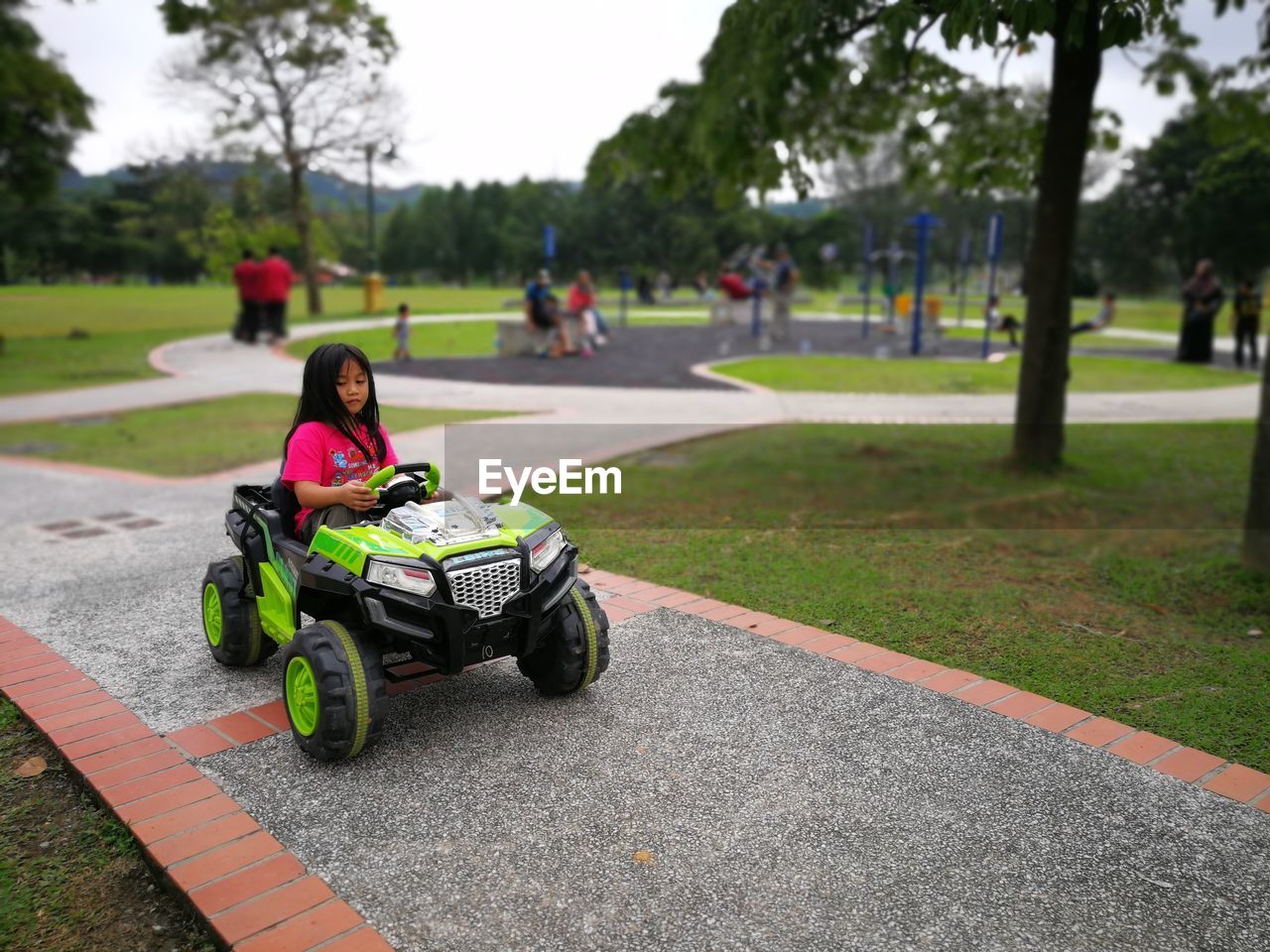 Girl riding beach buggy on footpath at park
