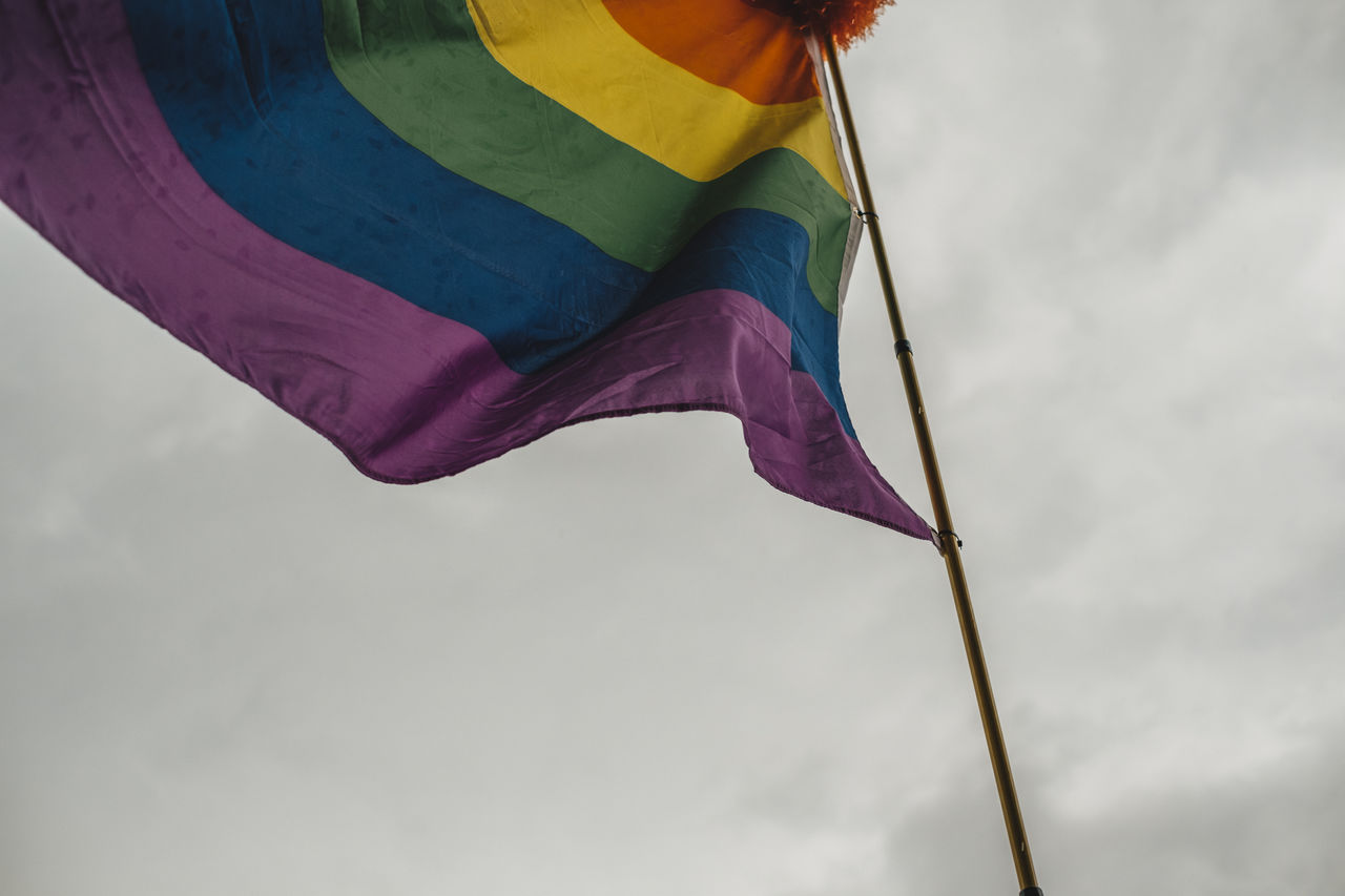 Low angle view of rainbow flag against sky