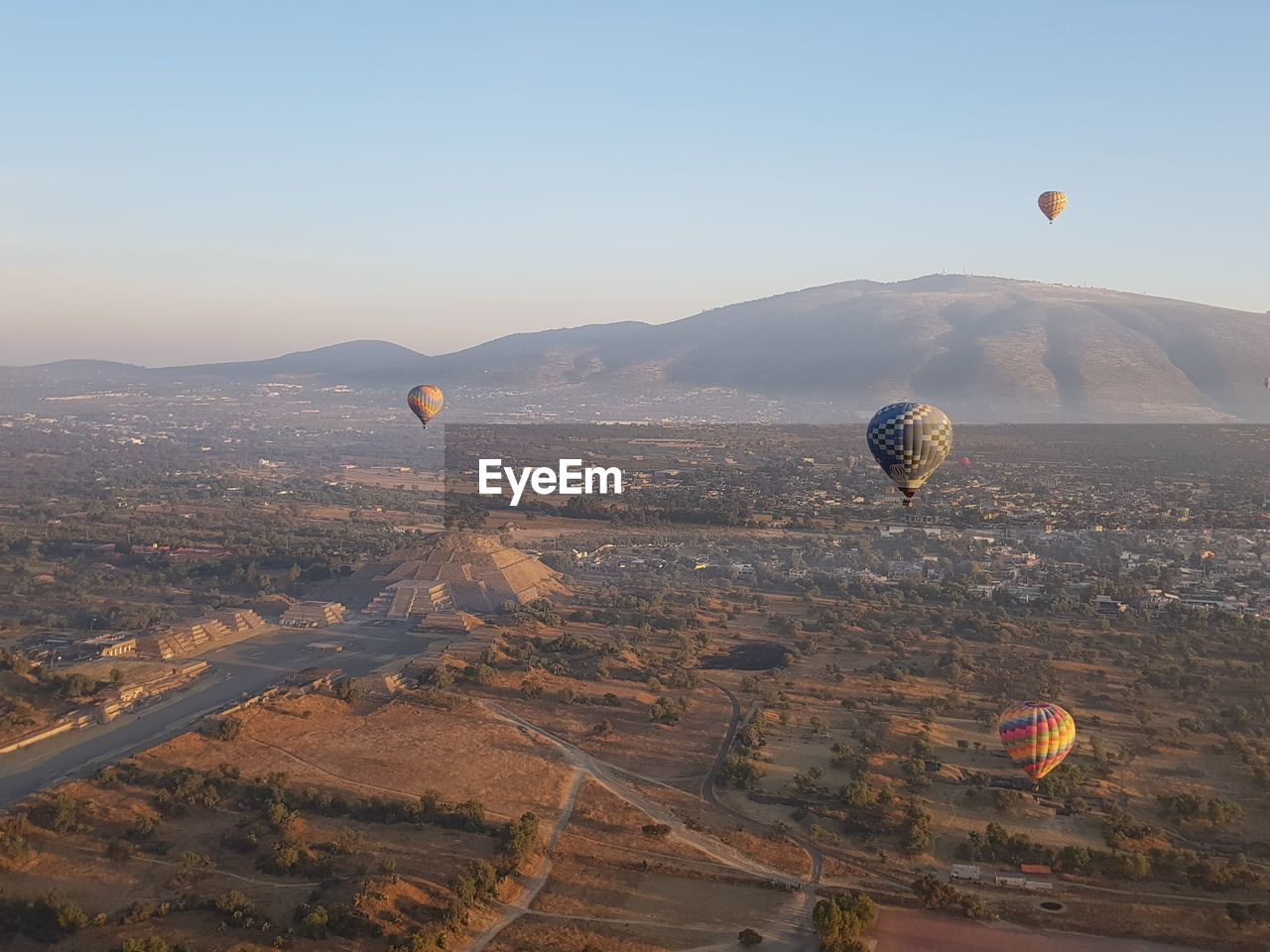 Hot air balloons flying over ancient pyramid