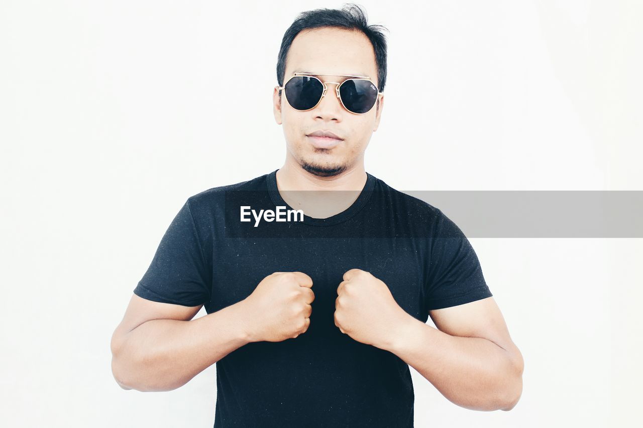 Portrait of young man wearing sunglasses against white background