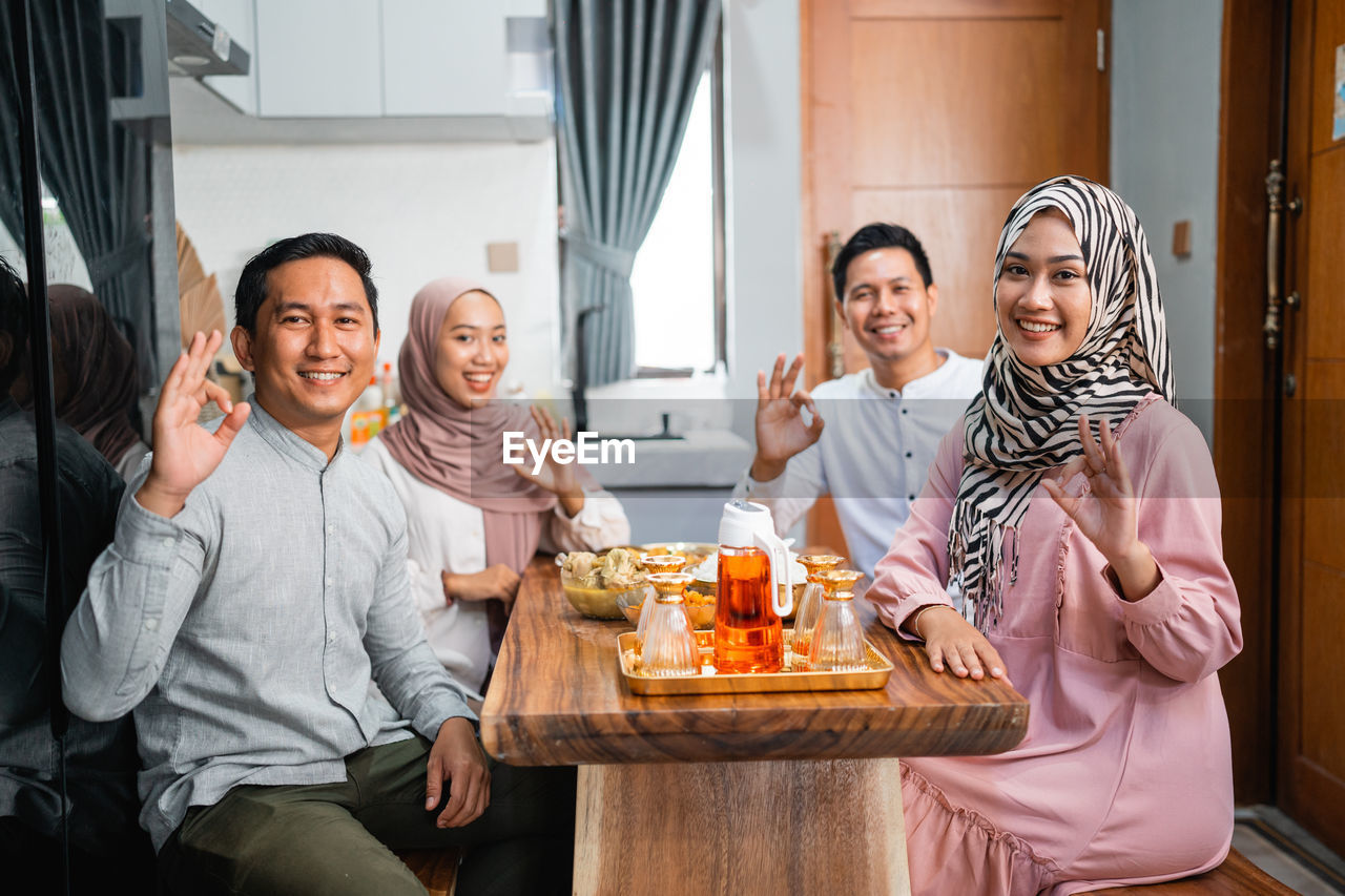 portrait of smiling friends sitting on table