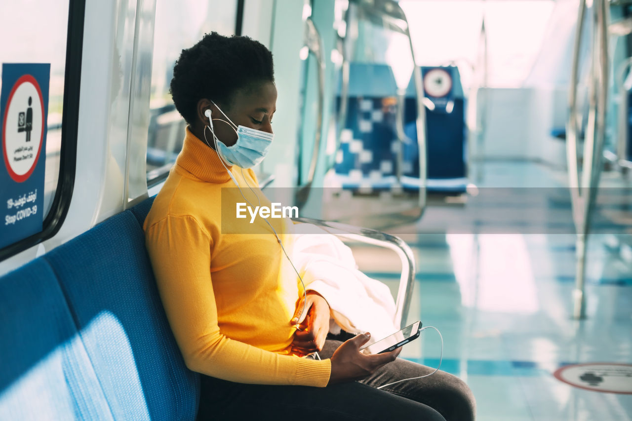 A young african woman in a protective mask rides the subway 