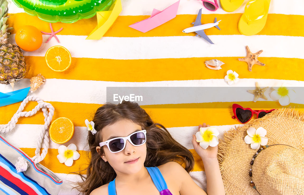 portrait of young woman holding sunglasses while sitting on table