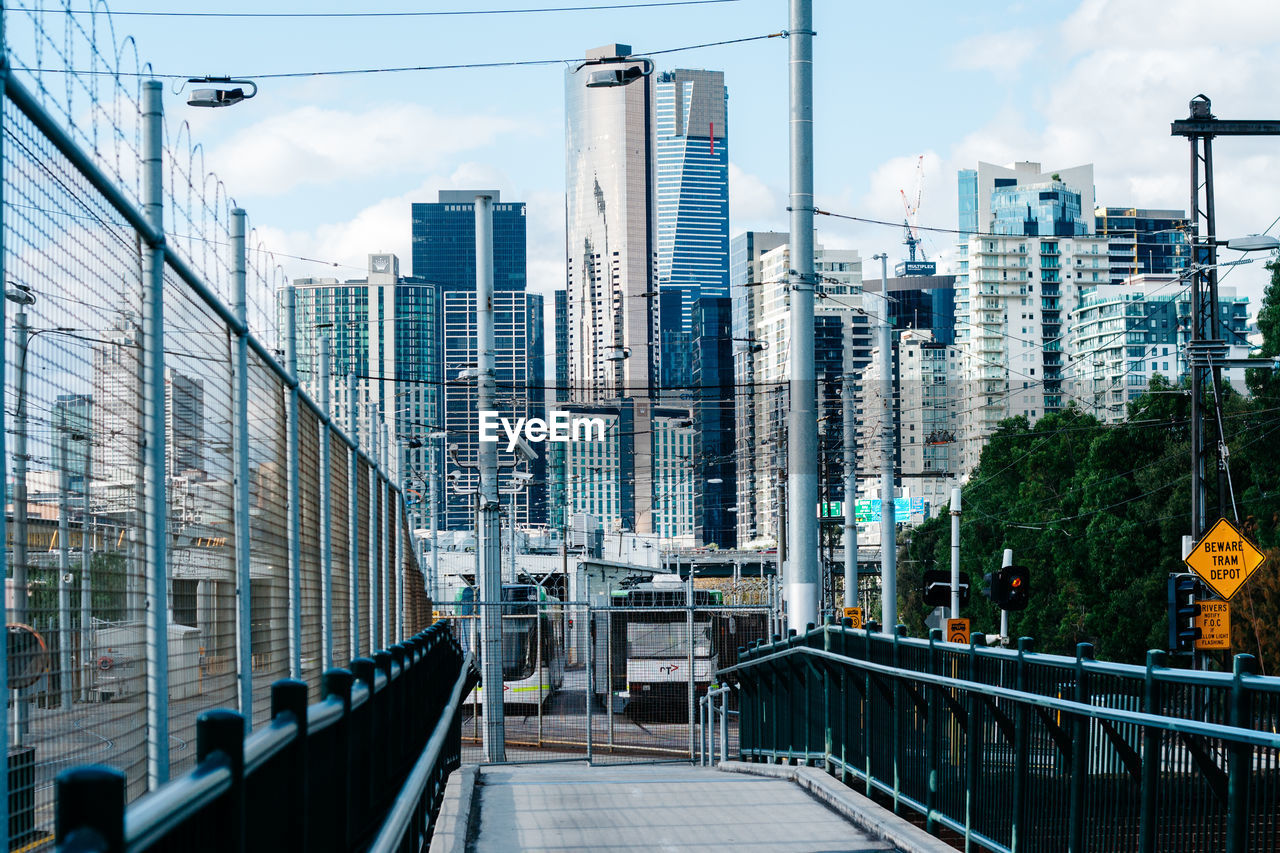 Footbridge amidst buildings in city against sky
