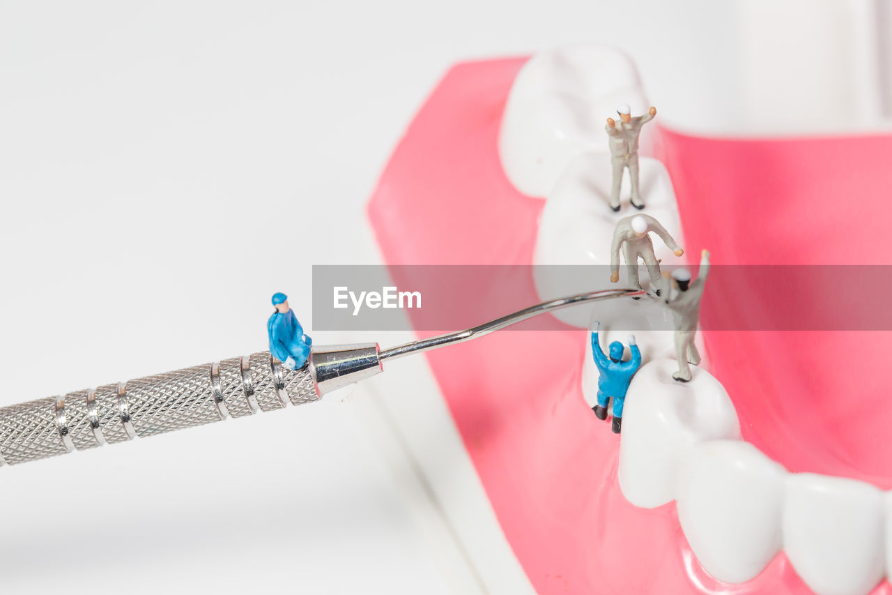 Close-up of figurines repairing dentures over white background