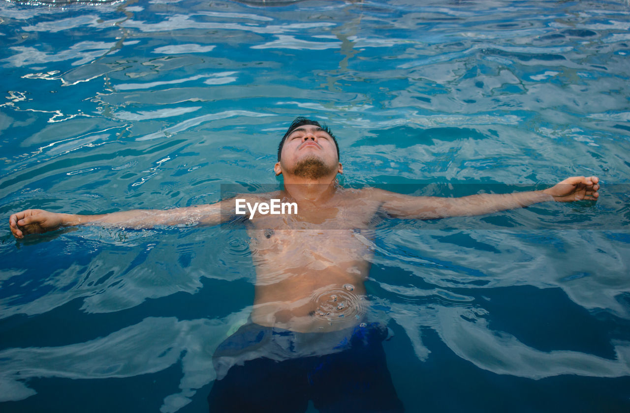High angle of shirtless man swimming in pool