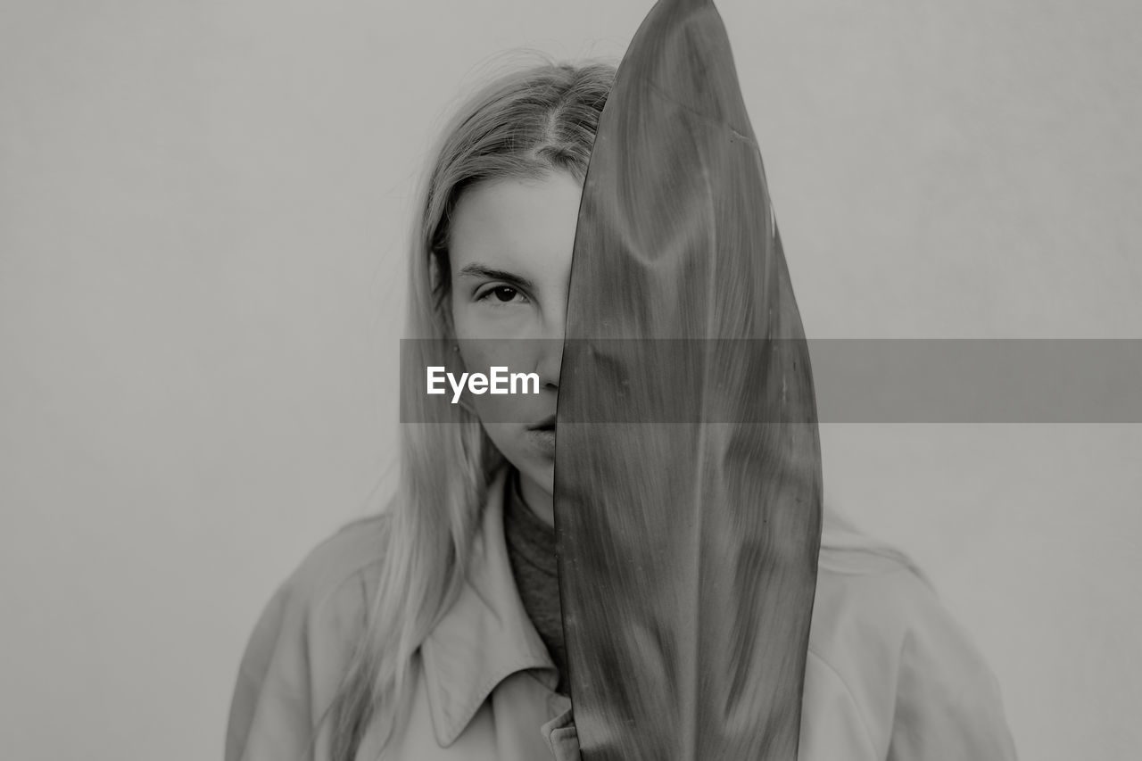 A portrait of a young woman holding a plant leaf